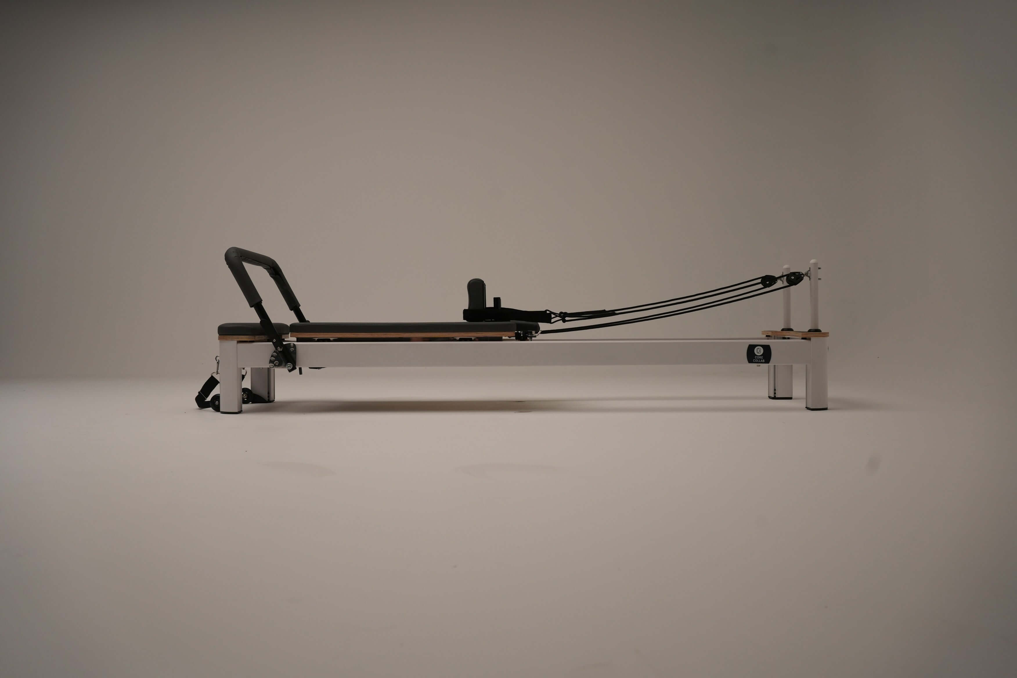 Core Collab Queen Studio Pilates reformer side view on a white background.