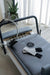 The Core Collab Queen Reformer with tower shown in white with grey upholstery at the footbar end with a Pilates magic circle and ankle weights.