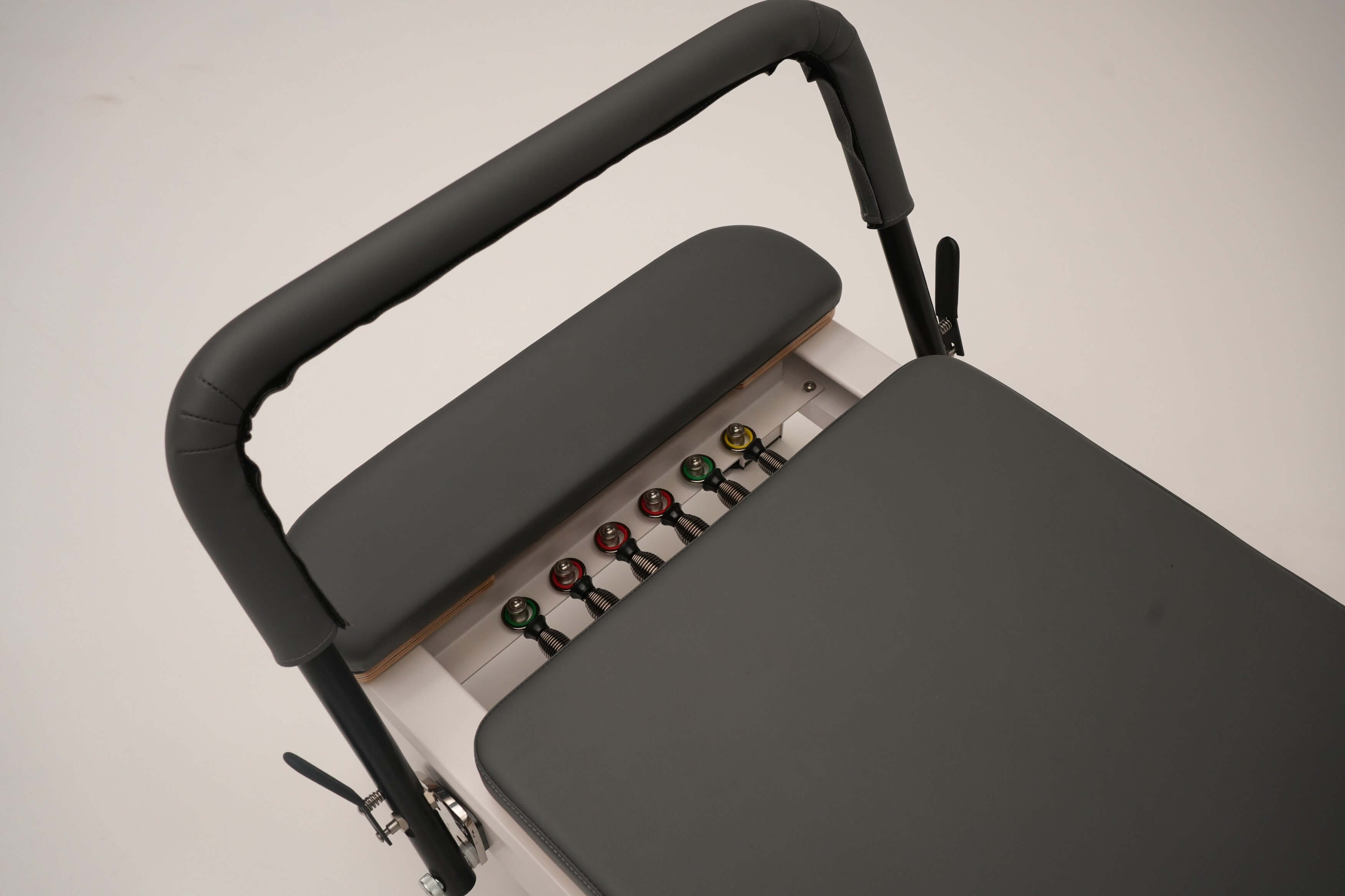 Close up of the Core Collab Queen Pilates reformer showing the footbar and 6-spring system of 3 reds, 2 greens and 1 yellow spring.