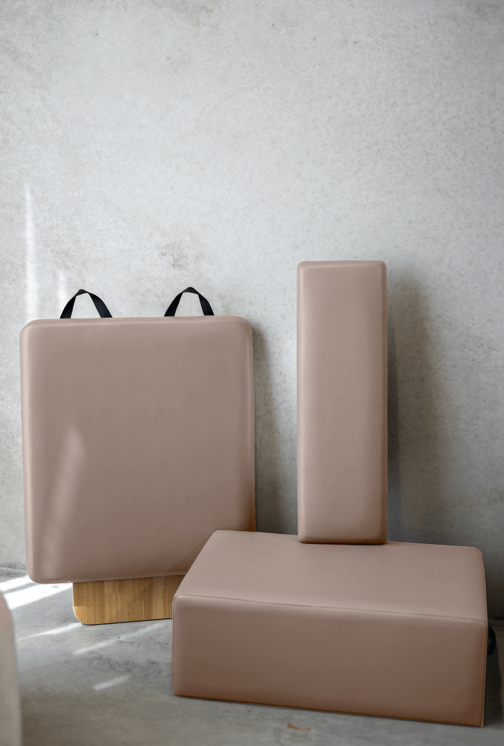 Set of accessories included with the Core Collab Eco Pilates Reformer, showing pink upholstery on the sitting box, jumpboard and platform cushion.