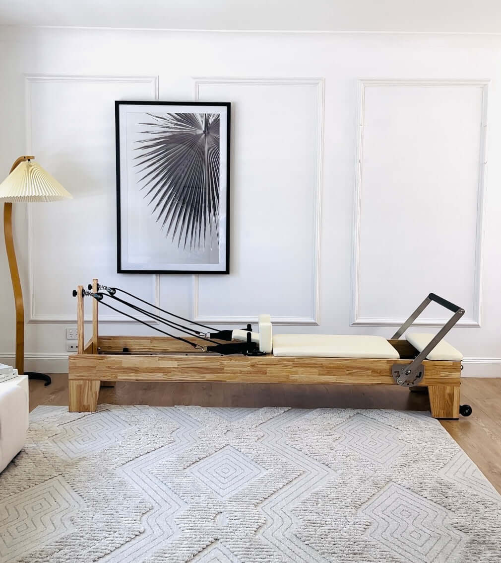 Core Collab Eco Warrior Pilates reformer showing beechwood frame and beige upholstery in a living room setting.