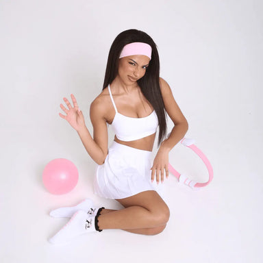 Woman in white outfit with pink accessories, wearing white socks with black ruffles and images of cats.