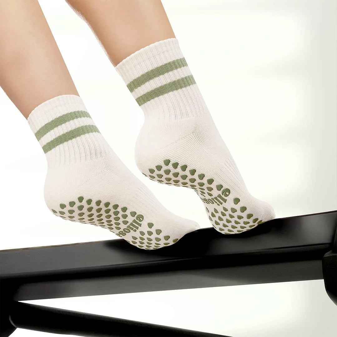 Elliosa Dual direction grip socks in matcha cream stripe worn by someone using a Pilates reformer.