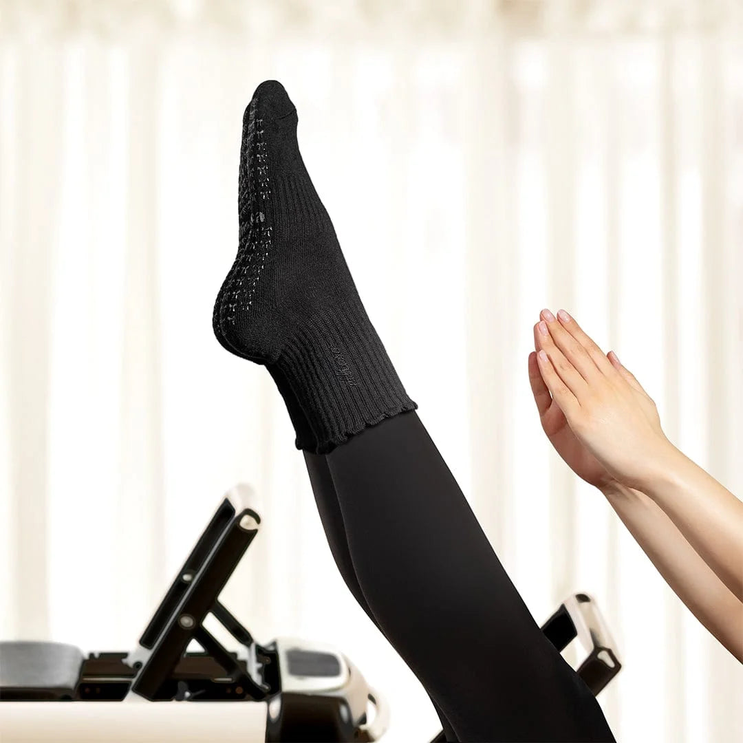 Elliosa dual direction basic black grip socks shown on person doing Pilates on a reformer.
