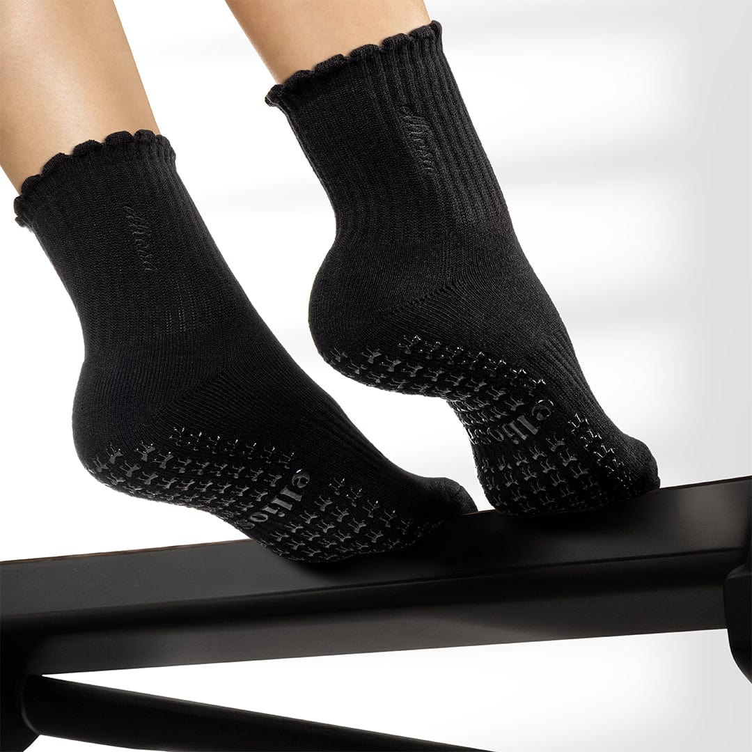 Elliosa dual direction black grip socks shown on person using Pilates reformer
