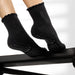 Elliosa dual direction black grip socks shown on person using Pilates reformer