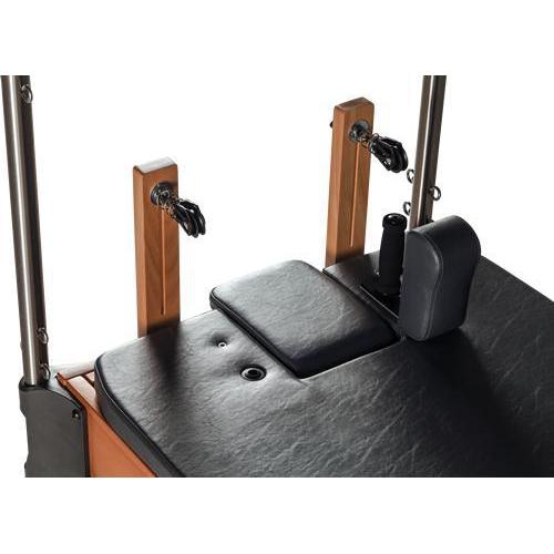 close up of a pilates reformer showing the black head and shoulder cushions and pulleys.