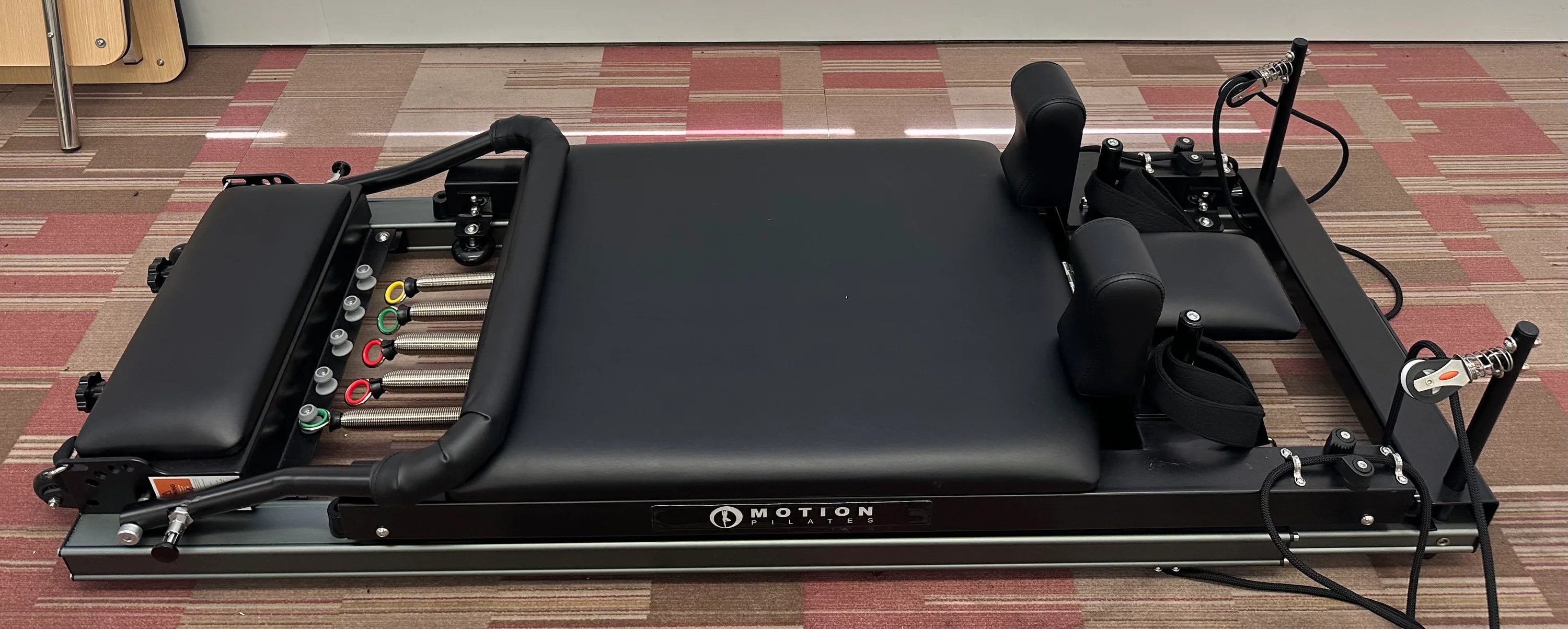 Black pilates reformer folded on the floor.