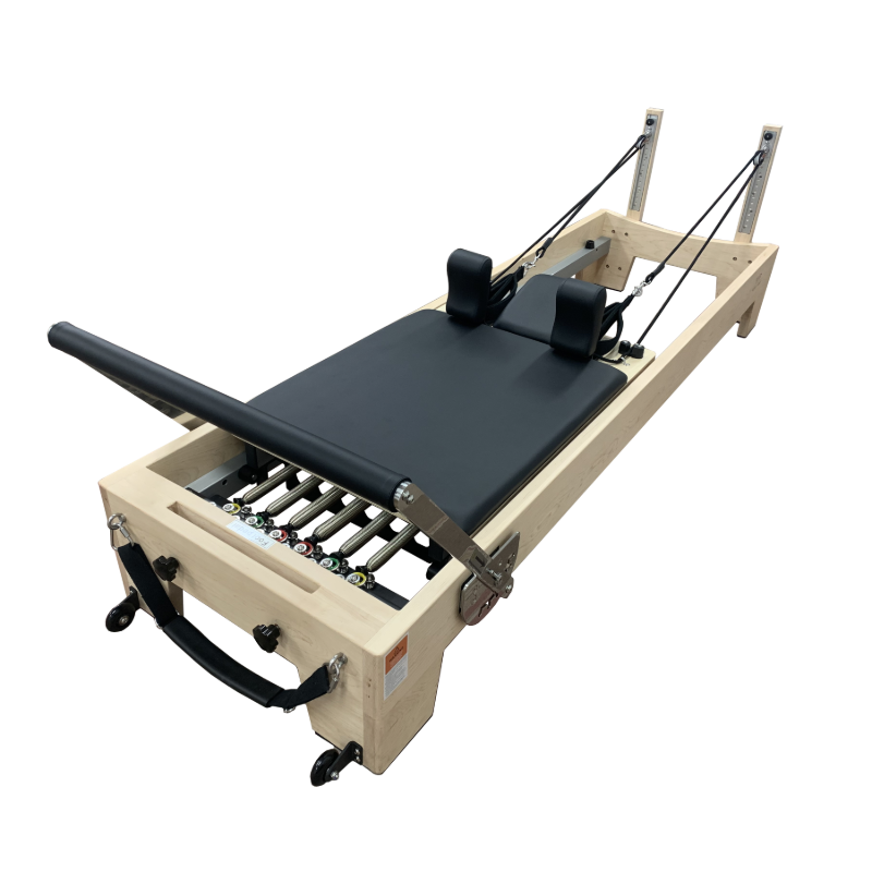 Light coloured wooden pilates reformer with black upholstery and 6 colour coded springs.