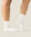Side view of white crew grip socks above ankles with white grips on sole.