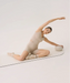 Woman doing pilates on a mat wearing beige outfit with matching beige socks with white stripes.
