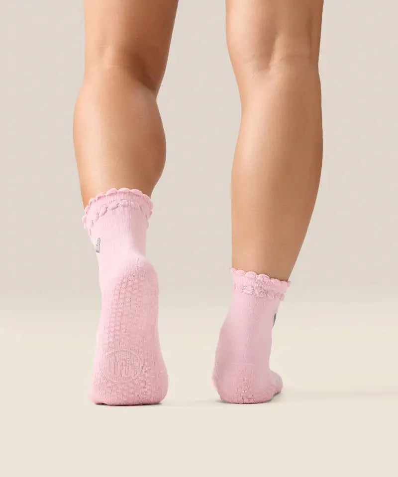 Rear view of pink moveactive heart ruffle socks with grips and logo visible on sole.