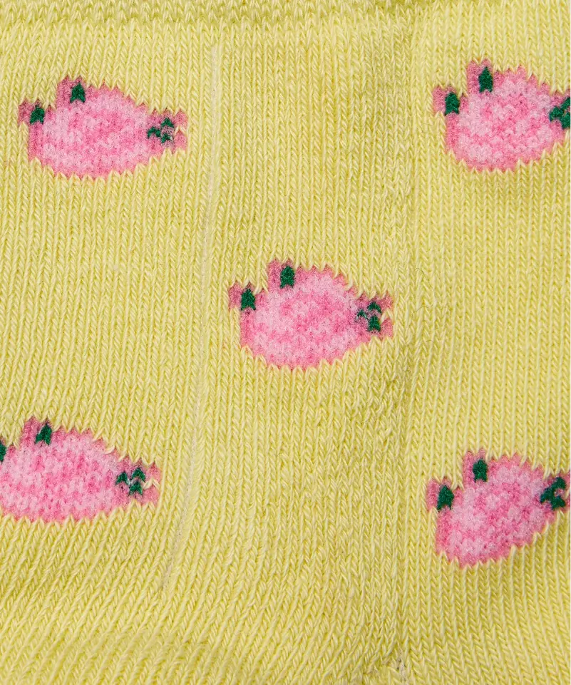 Close up of yellow grip socks with small pink flowers.