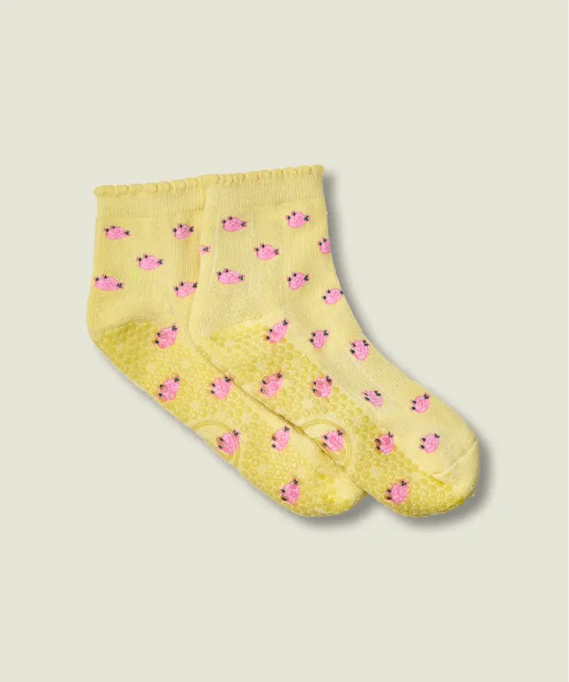 Yellow quarter crew grip socks just above ankle, with ruffle at the top, small pink flowers, and yellow grips and MoveActive logo on the sole.