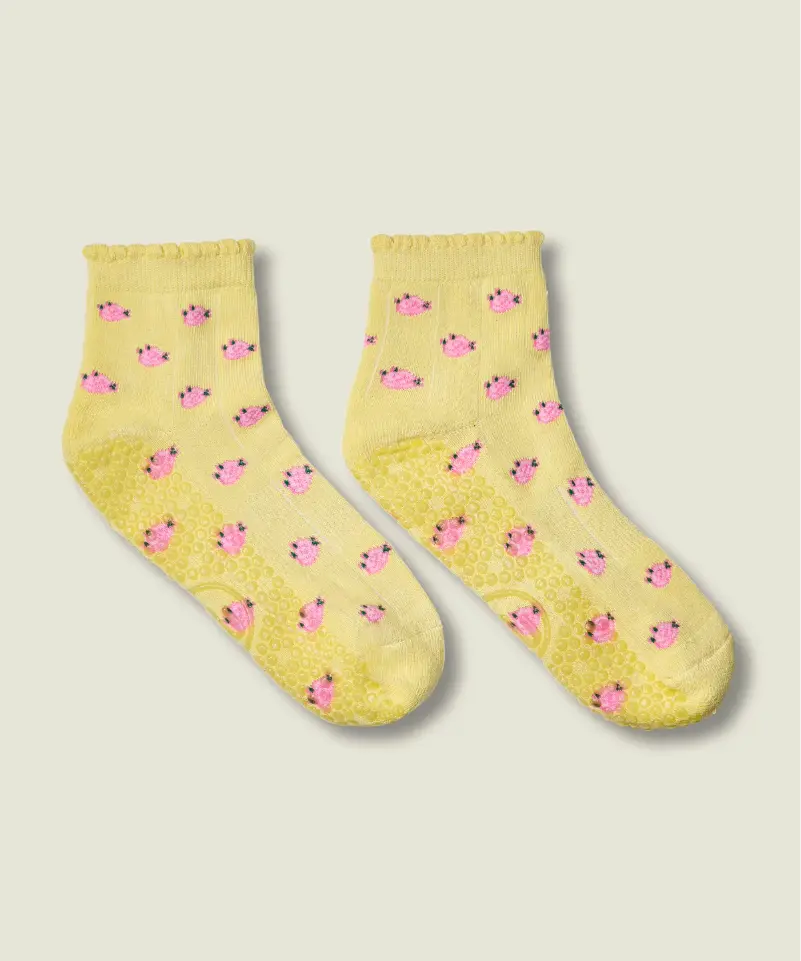 Yellow quarter crew grip socks just above ankle, with ruffle at the top, small pink flowers, and yellow grips and MoveActive logo on the sole.