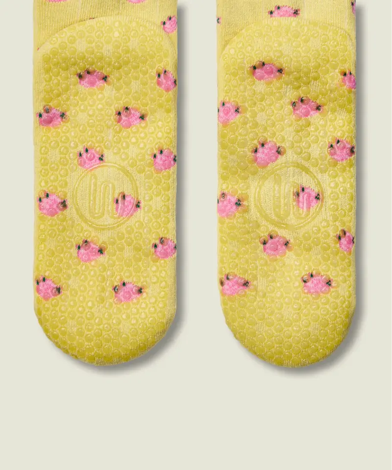 Sole view of yellow grip socks with small pink flowers, and yellow grips and MoveActive logo on the sole.