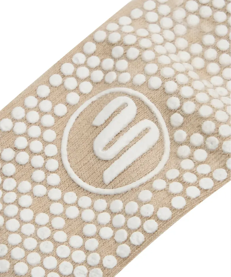 Close up of the sole of moveactive grip socks in beige colour with white grips and white logo.