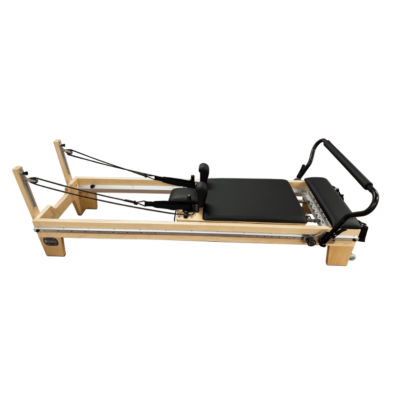 Light coloured wooden pilates reformer with black upholstery and steel track running the entire length of the reformer. 