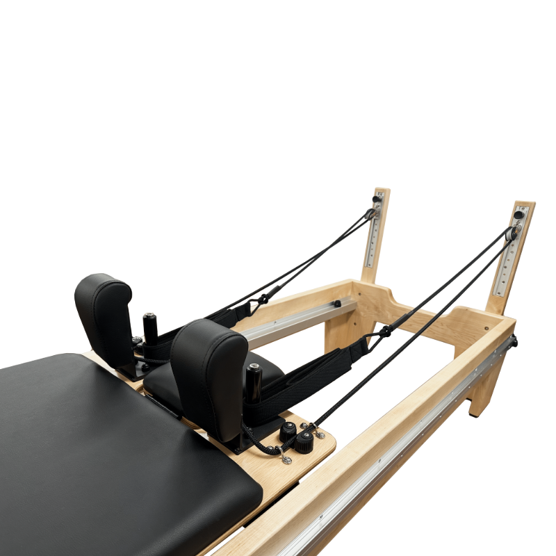 Close up of clinical pilates reformer with black upholstery at the shoulder and head cushions.