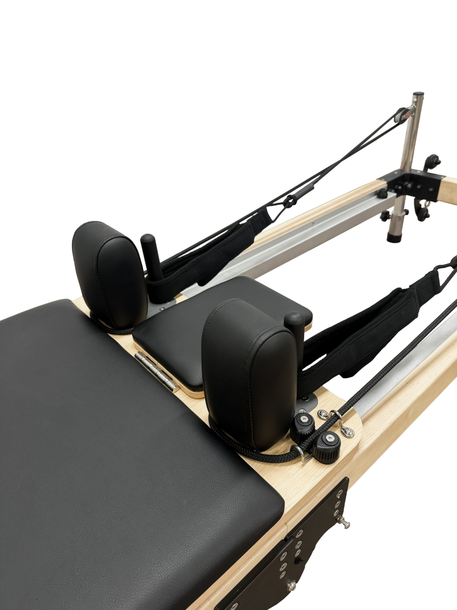 Close up view of pilates reformer with black head and shoulder cushions.