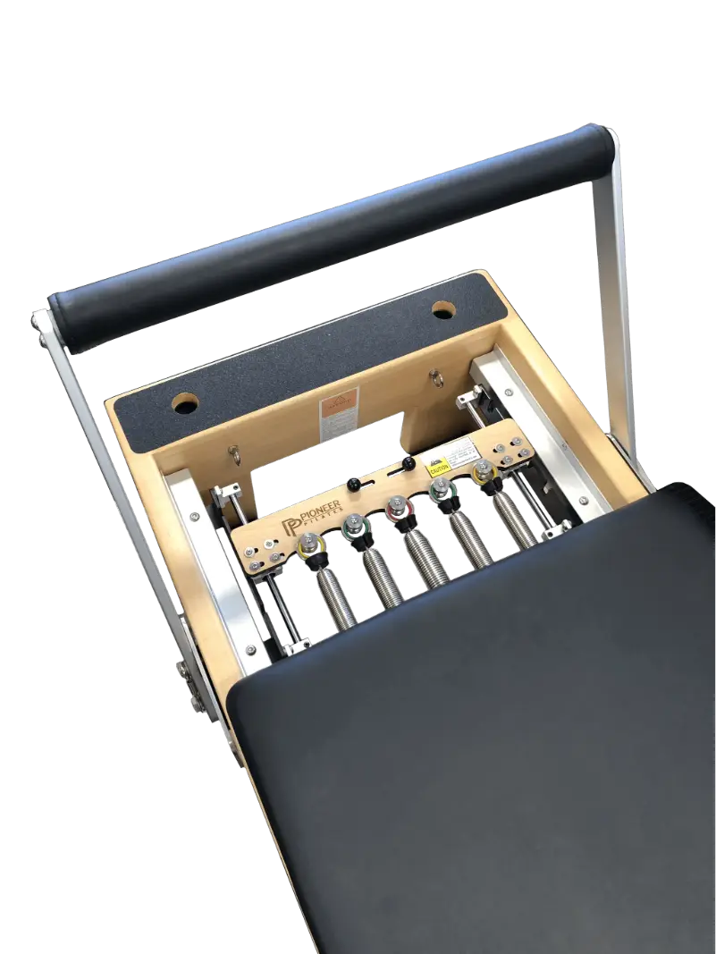 close up of wooden reformer pilates table at the footbar and showing 5 springs. The reformer has black upholstery.