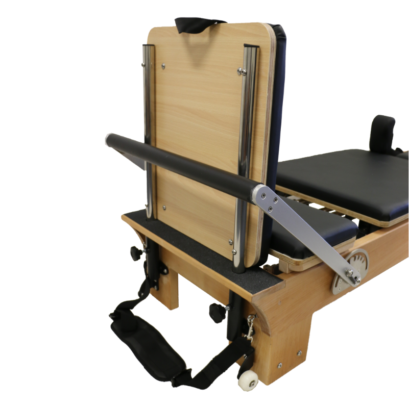 close up of foot end of wooden reformer pilates machine showing white wheels, adjustable footbar and jump board attachment.