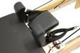 close up of reformer pilates machine with black upholstery, showing the head and shoulder cushions.