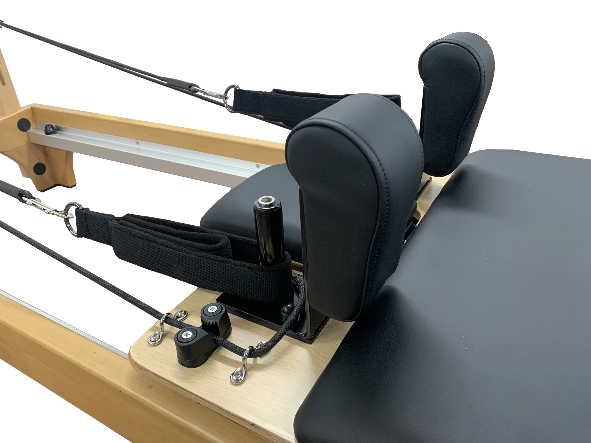 Close up of a pilates reformer machine with wooden frame and black cushioned seat showing the head and shoulder rest and ropes.
