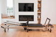 Foldable metal pilates reformer in a home setting with a fireplace and television.