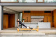 Woman exercising on a Pioneer Pilates PP-09 reformer in kitchen