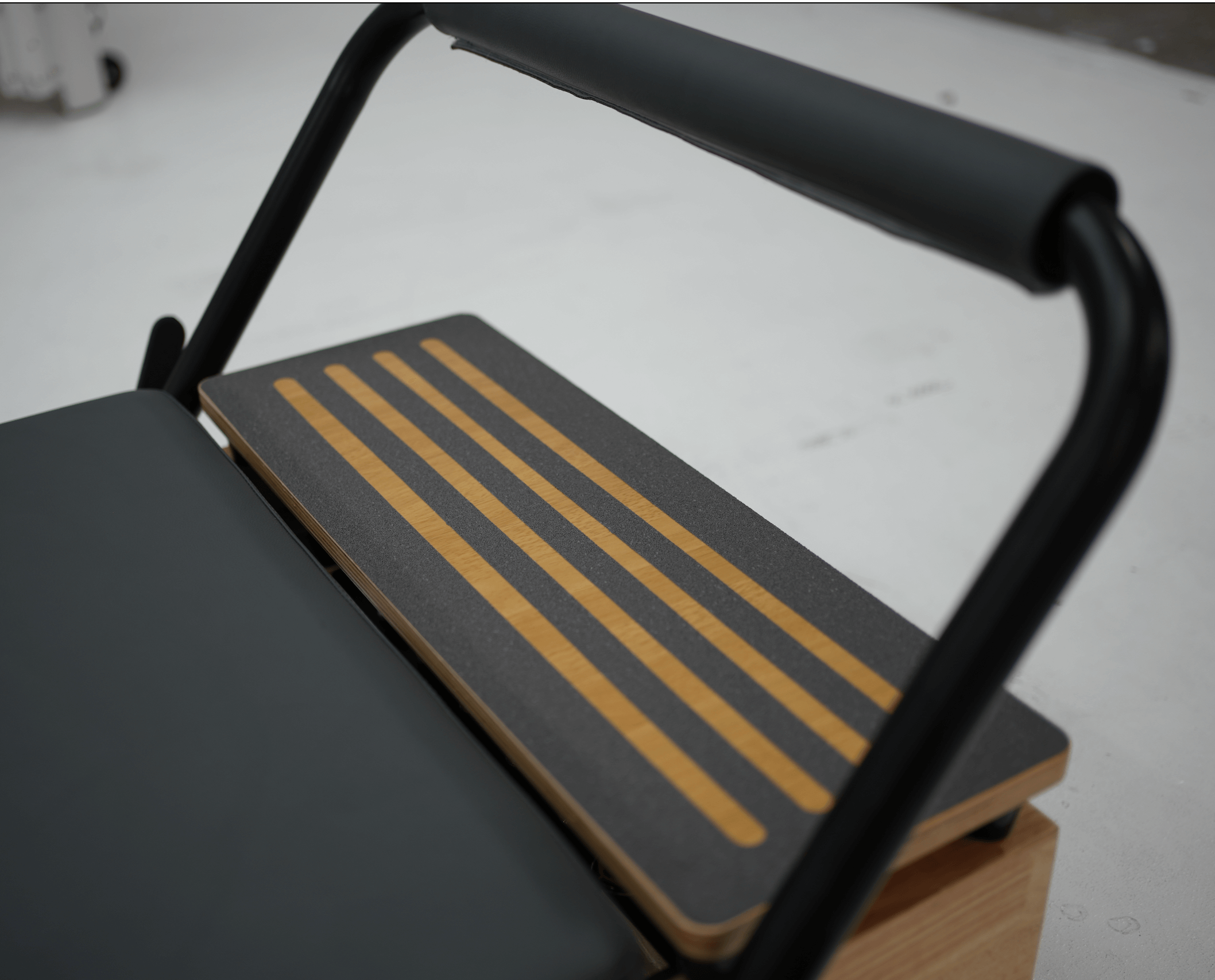 Wooden platform extender with black non-slip integration to extend the Pilates reformer.