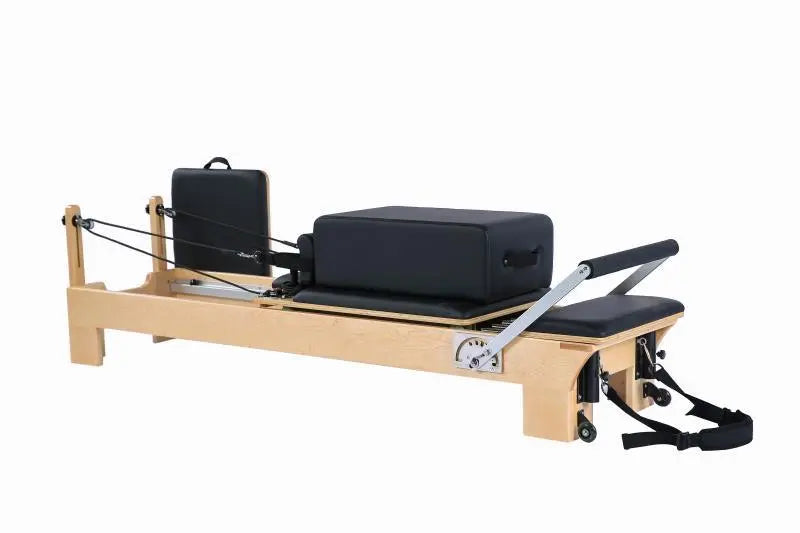 Light coloured wooden pilates reformer with black upholstery, with a black sitting box and jump board and black leads.