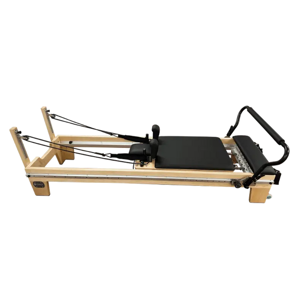 Light coloured wooden clinical full track Pilates reformer with black upholstery and steel track running the entire length of the reformer. 