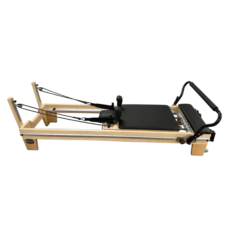 Light coloured wooden clinical full track Pilates reformer with black upholstery and steel track running the entire length of the reformer. 