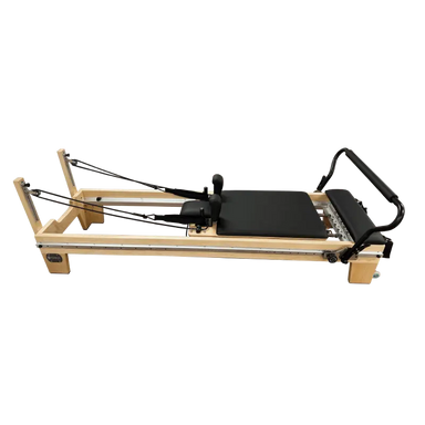 Light coloured wooden clinical full track Pilates reformer with black upholstery and steel track running the entire length of the reformer. 