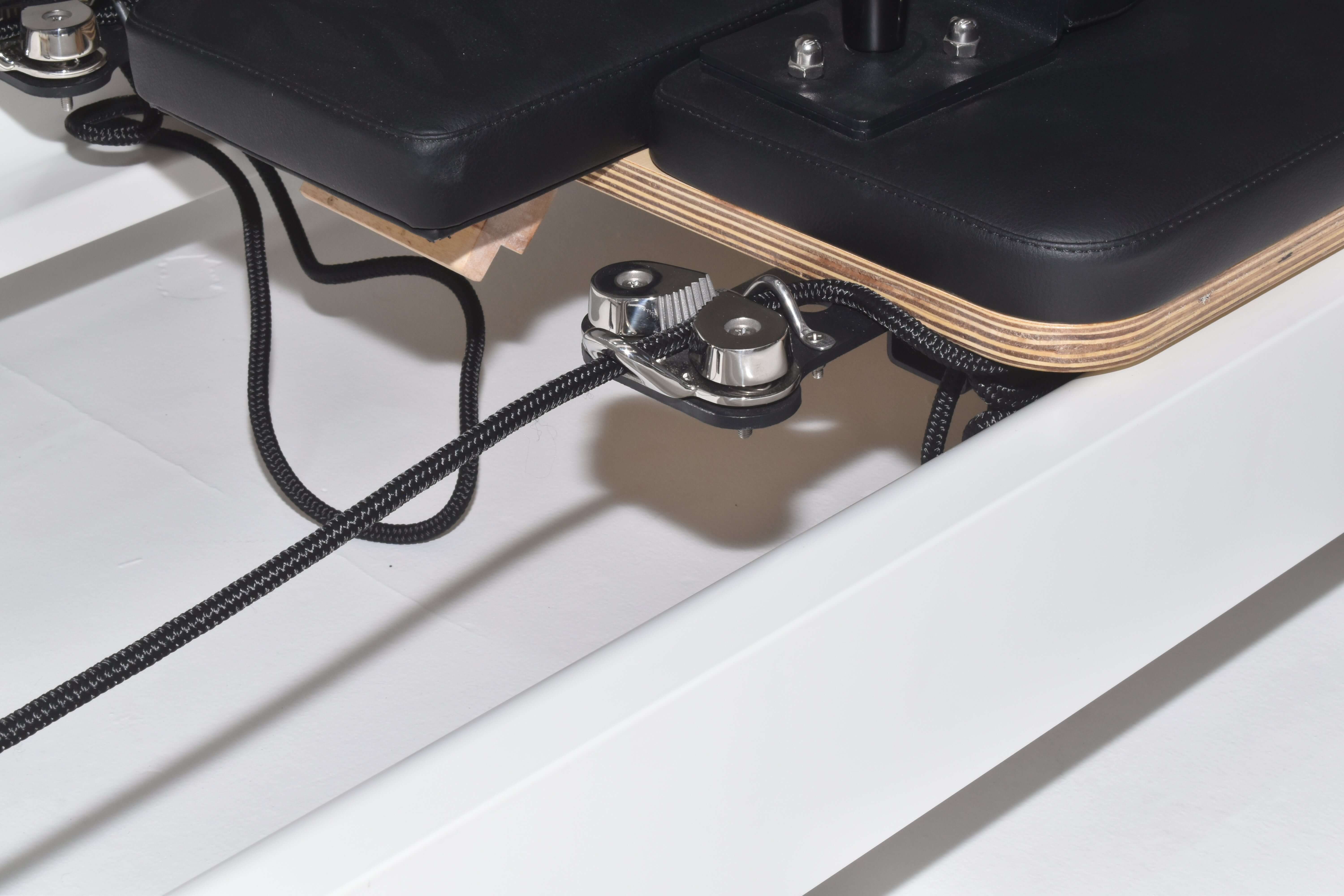 Close up of the cleat rope lock mechanism on the Queen 2.0 Pilates reformer with white frame and black upholstery.