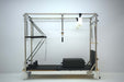 Core Collab Queen Pilates Reformer with Full Trapeze side view with black upholstery.