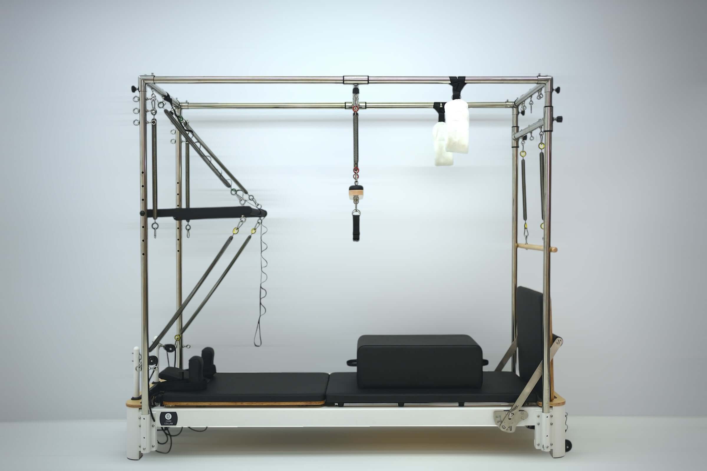 Core Collab Queen Pilates Reformer with Full Trapeze side view with black upholstery.