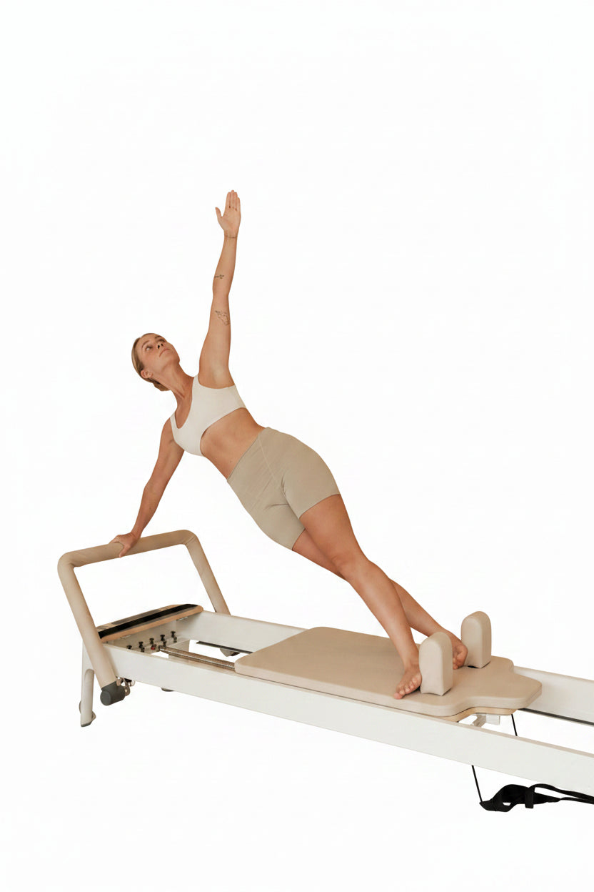 woman using a reformer Pilates machine on a white background.