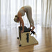 Woman using a Pilates Wunda Chair in a home studio set up.