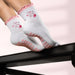 White socks with pink ruffles and the words "pilates princess" emrboidered with pink images, and pink bow shaped grips on the soles.
