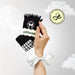 hand holding black socks with "Pilates Social Club" embroidered around a bow, with white ruffles at the ankle and white bow shaped grips on the soles.