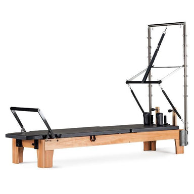 A stylish pilates reformer with trapeze attachment at the head end.