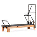 A stylish pilates reformer with trapeze attachment at the head end.