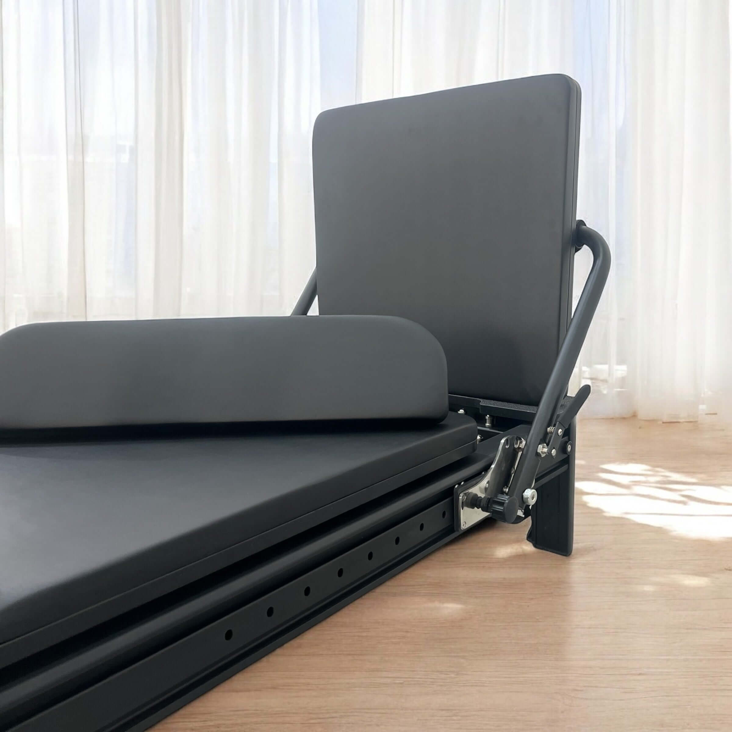 Close up of the core collab queen Pilates reformer in black frame and upholstery showing the jumpboard.