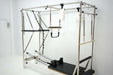 Angled view of Core Collab queen Pilates reformer with full trapeze with attachments on a white background.