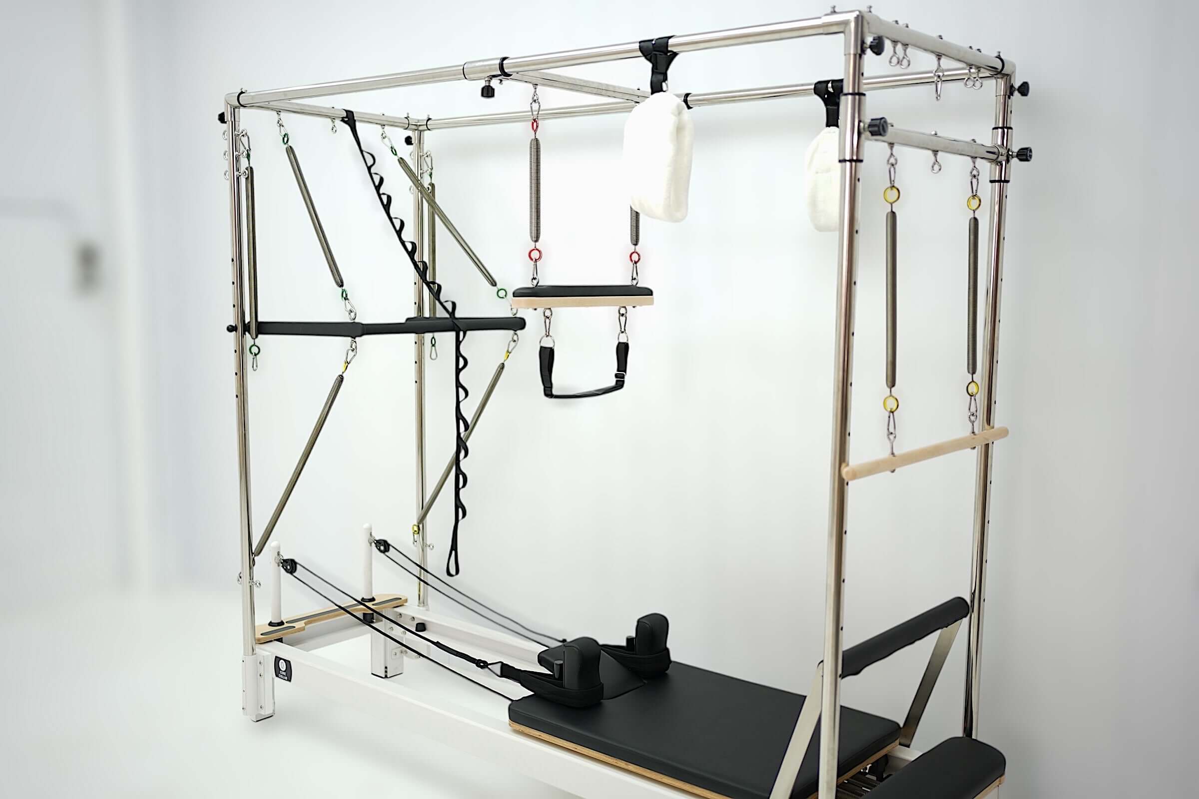 Angled view of Core Collab queen Pilates reformer with full trapeze with attachments on a white background.